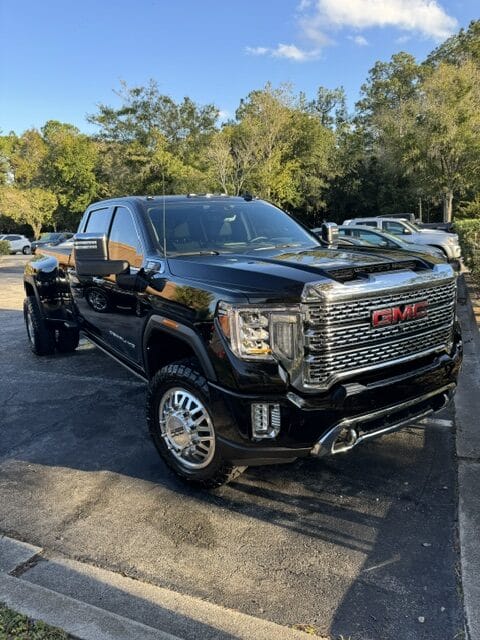 A close-up view of a shiny car hood reflecting light, showcasing a pristine finish and detailing work.