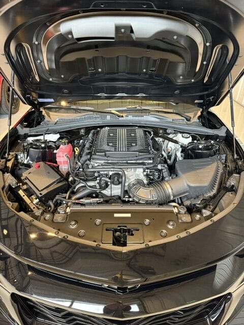 A detailed view of a shiny car hood reflecting light, showcasing the quality of Moran's Performance Detailing services.