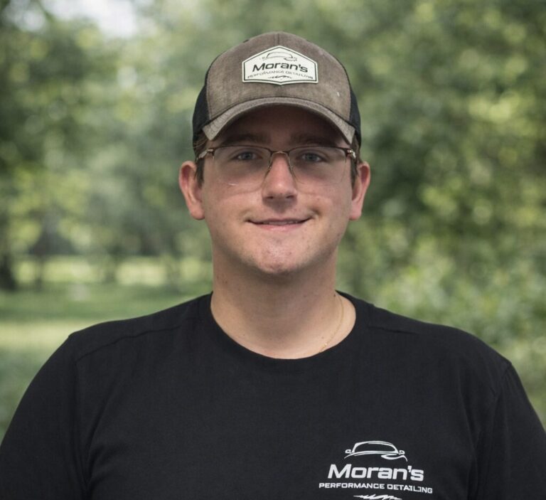 Moran Scott stands confidently in a detailing shop, showcasing expertise in premium detailing Jacksonville FL.