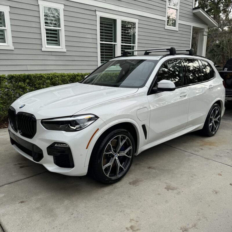 A detailed view of a shiny black car exterior, showcasing a flawless finish and reflections, emphasizing quality detailing.