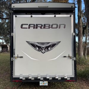 A close-up of a shiny black car hood reflecting the surrounding environment, showcasing Moran's Performance Detailing service