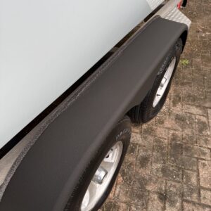 A close-up shot of a shiny, detailed car hood reflecting light, showcasing a pristine finish and color.