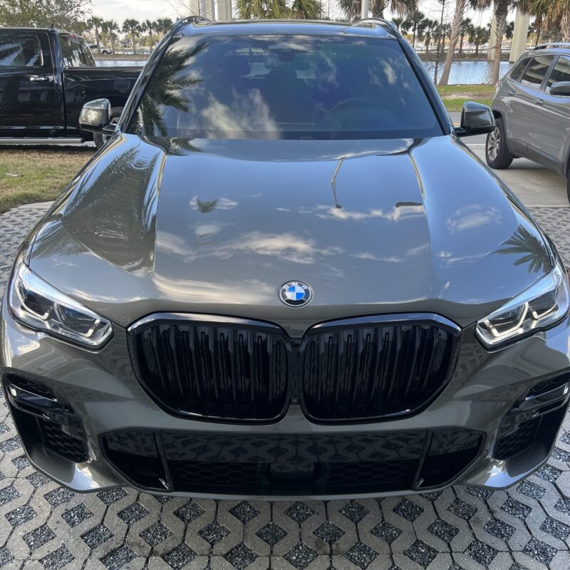 A detailed view of a shiny, well-polished car hood reflecting the surroundings, showcasing Moran's Performance Detailing expe