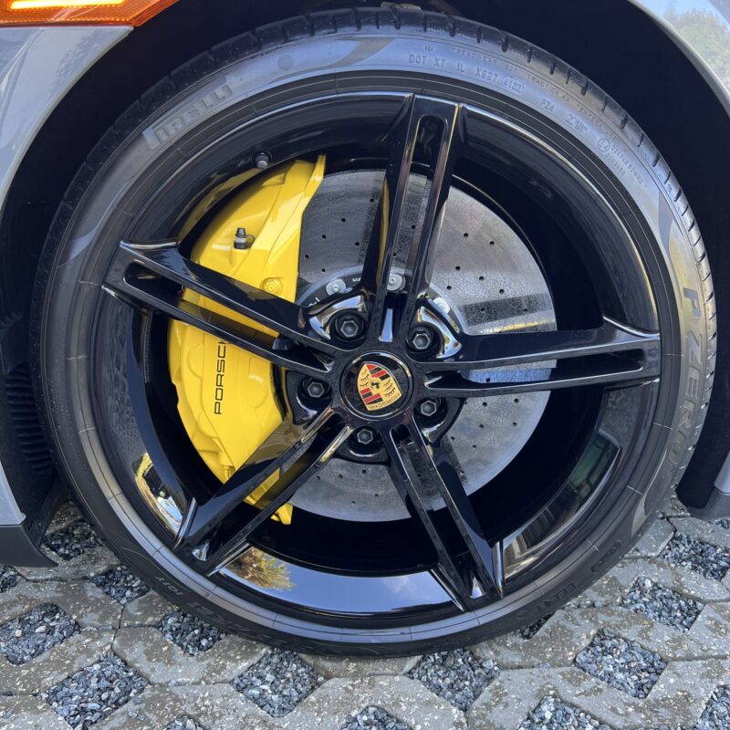 A close-up of a shiny car hood reflecting light, showcasing a detailed paint finish at Moran's Performance Detailing.