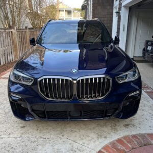 A close-up of a shiny, detailed car hood reflecting light, showcasing the quality of Moran's Performance Detailing services.