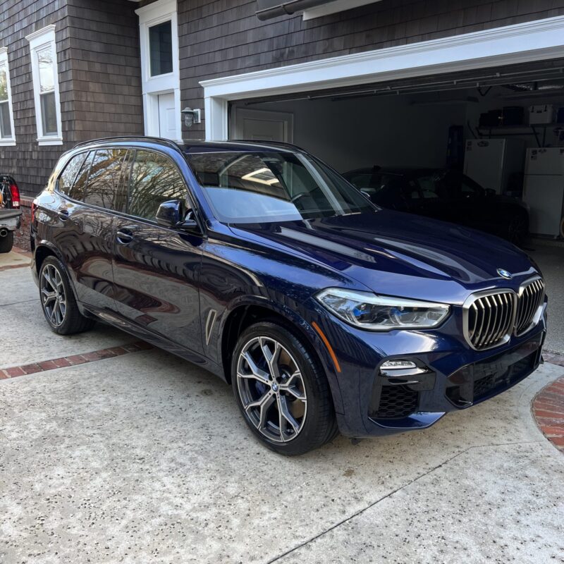 A detailed view of a shiny car hood reflecting light, showcasing the quality of Moran's Performance Detailing services.