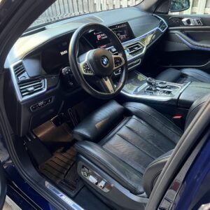A close-up of a shiny, detailed car surface showcasing a reflection of trees and sky, emphasizing the quality of detailing.