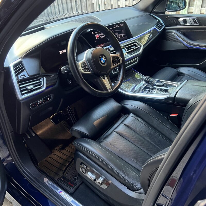 A close-up of a shiny, detailed car surface showcasing a reflection of trees and sky, emphasizing the quality of detailing.