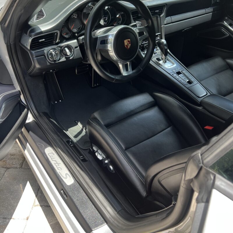 A close-up of a shiny car hood reflecting light, showcasing a professional detailing finish.